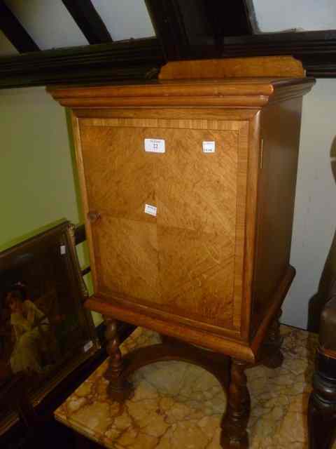 Appraisal: A WALNUT VENEERED POT CUPBOARD enclosed by single panel door