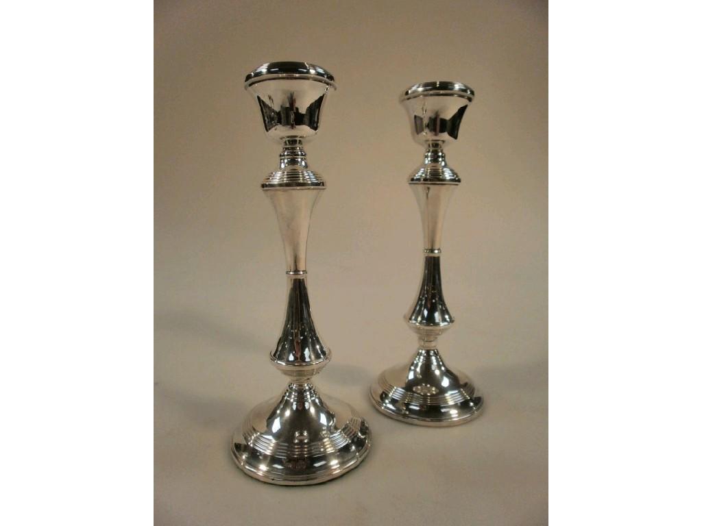 Appraisal: A pair of silver candlesticks with reeded sconces and waisted