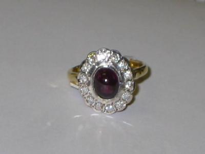 Appraisal: A CABOCHON GARNET AND DIAMOND CLUSTER RING the oval garnet