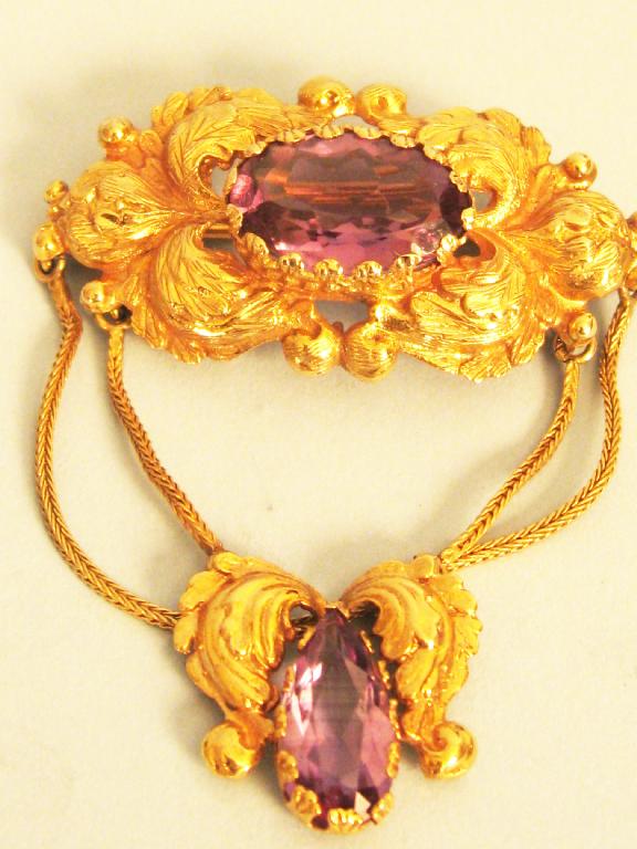 Appraisal: An Amethyst Brooch the oval-cut stone claw-set in embossed scrolled