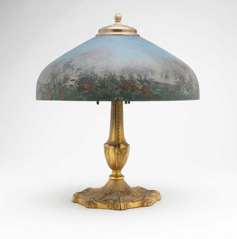 Appraisal: An Arts Crafts gilt-metal lamp with reverse-painted tropical landscape shade