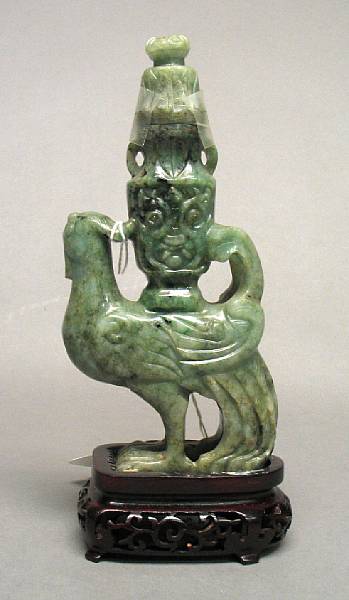 Appraisal: A mottled green jadeite phoenix Supporting a covered vase on