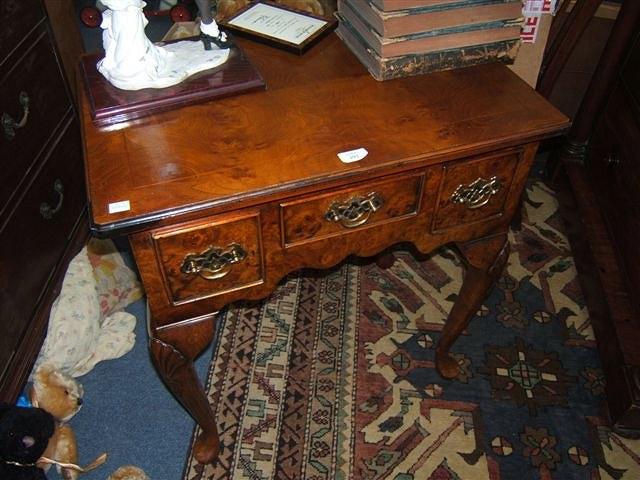 Appraisal: A yew wood veneered lowboy the small central drawer flanked