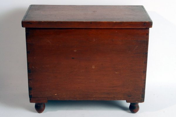 Appraisal: Dovetailed box with turned feet Lift lid with nailed molding