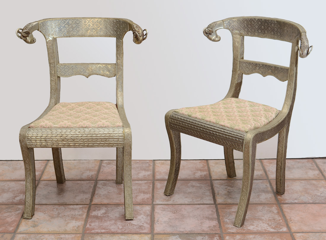 Appraisal: PAIR OF PERSIAN RAMS HEAD SIDE CHAIRS Embossed silver metal