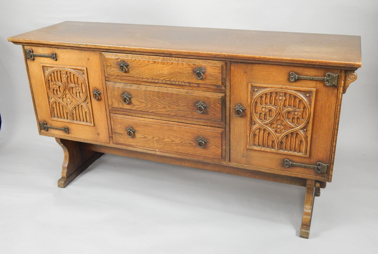 Appraisal: An oak sideboard with three drawers flanked by carved gothic