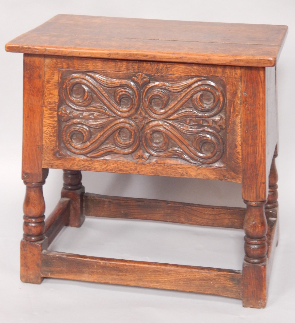 Appraisal: An oak coffer with a carved panel front raised on