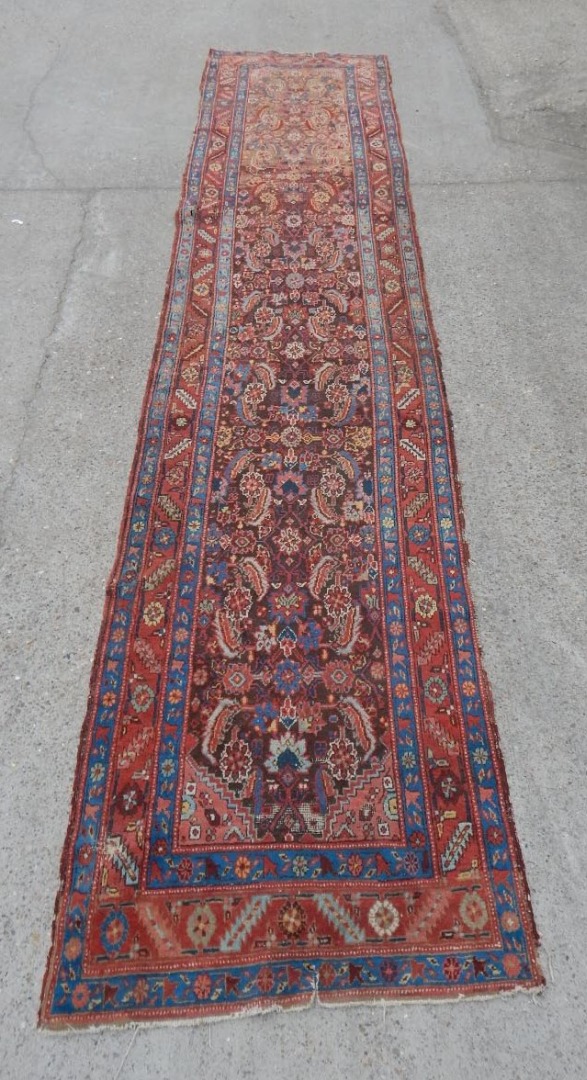 Appraisal: A Persian runner with a design of medallions red ground