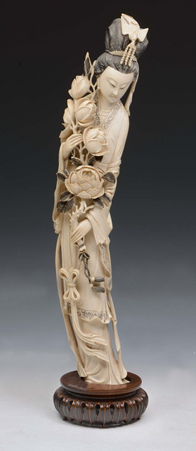 Appraisal: A CHINESE TALL CARVED IVORY MODEL OF GUANYIN holding lotus