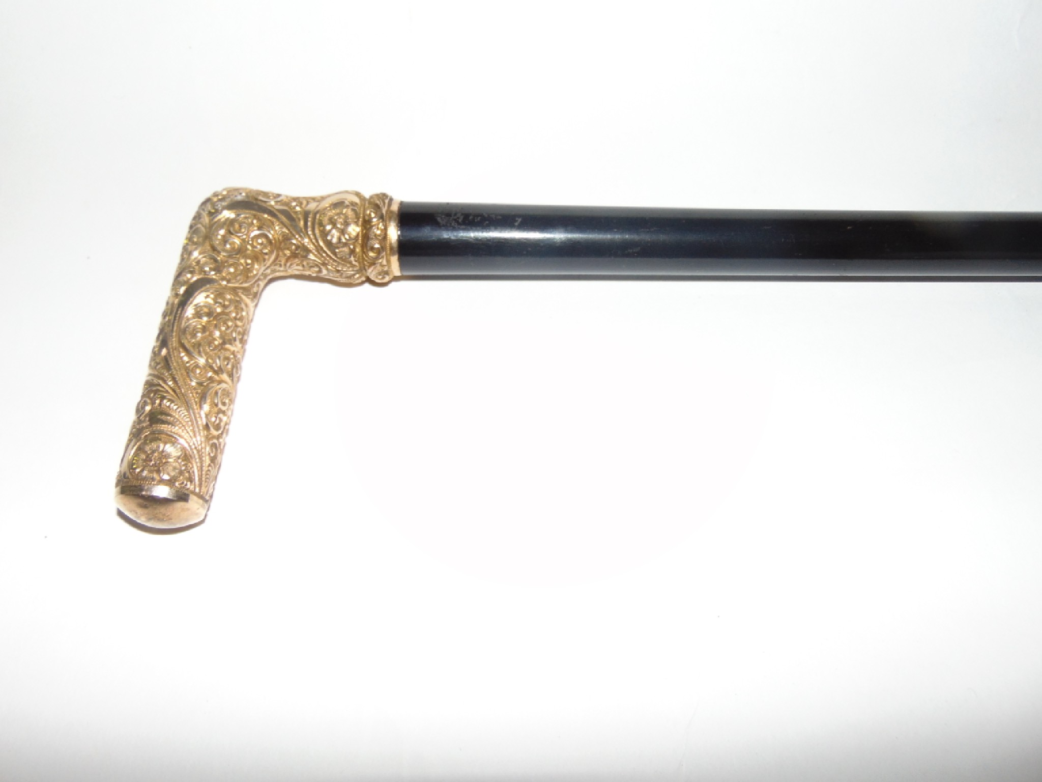 Appraisal: An antique ebony walking cane terminating in a gilded metal