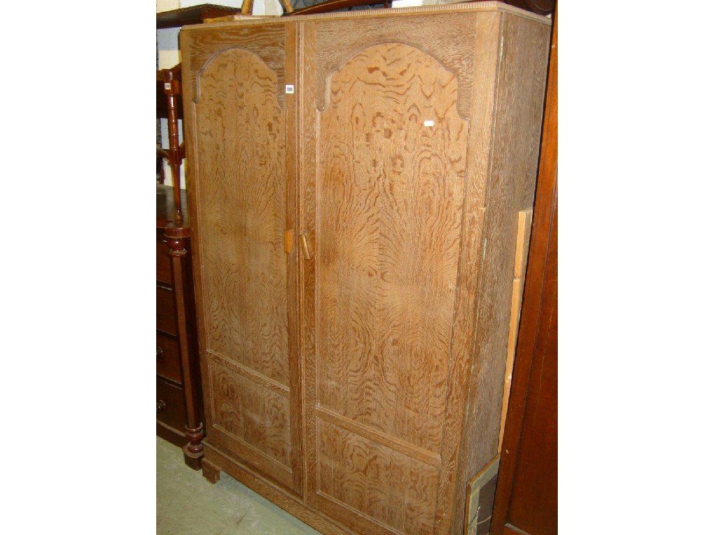 Appraisal: A limed oak double wardrobe with panelled decoration and turned