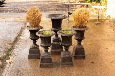 Appraisal: Four cast iron campana-shaped vases of fluted form on square