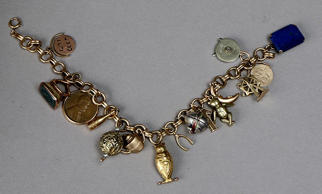 Appraisal: A GOLD CHARM BRACELET with sixteen attached charms one of