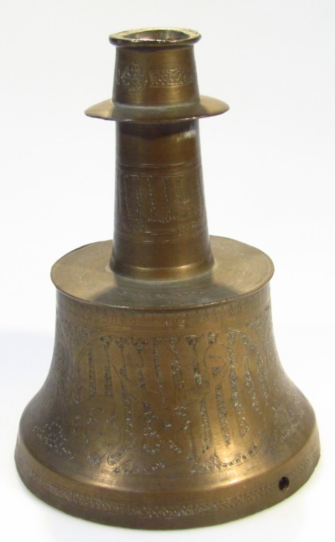 Appraisal: A Fars Khorasan style engraved brass candlestick The curved conical