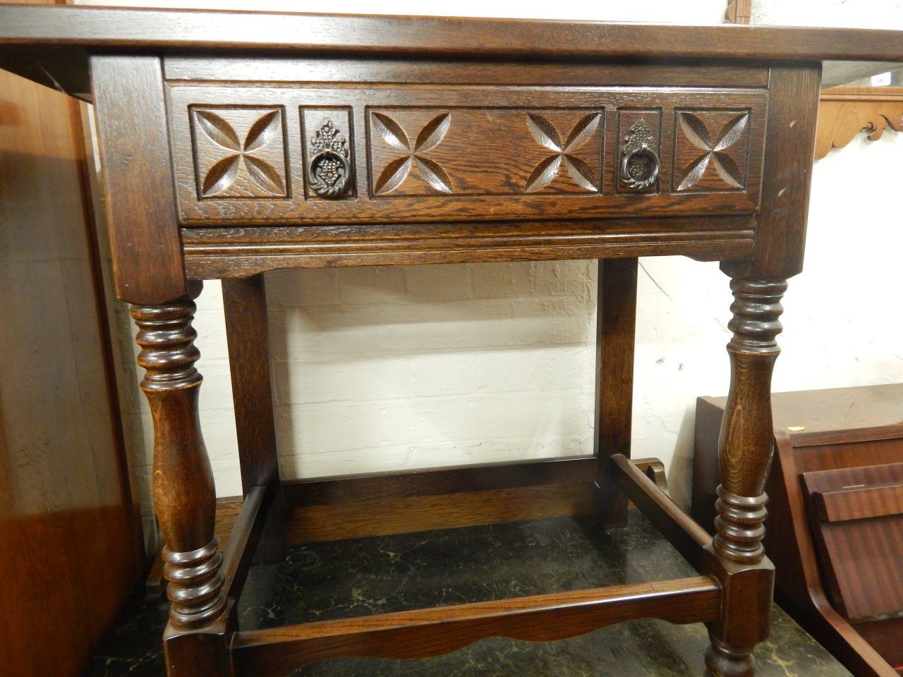 Appraisal: A reproduction oak side table with a carved frieze drawer