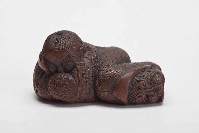 Appraisal: A JAPANESE WOOD NETSUKE reclining sleeping Shojo Iwami School signed