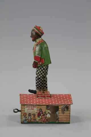 Appraisal: JAZZBO JIM Stauss lithographed tin figure on roof of cabin