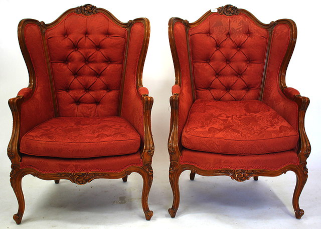 Appraisal: A PAIR OF CONTINENTAL UPHOLSTERED WING BACK ARMCHAIRS with carved