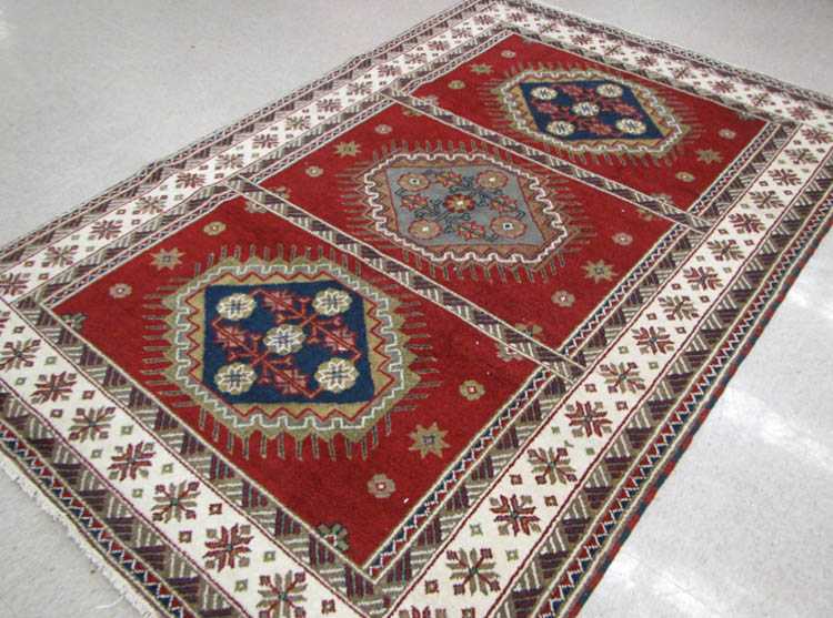 Appraisal: HAND KNOTTED ORIENTAL CARPET Indo-Kazak three geometric medallion design on