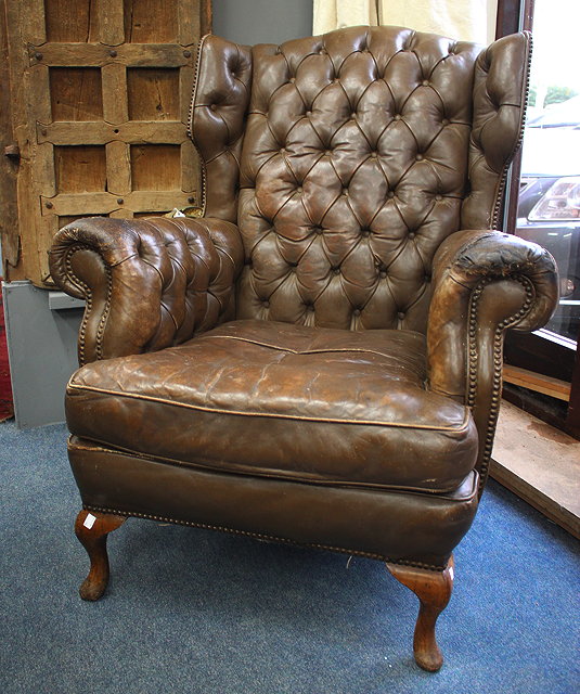 Appraisal: A BROWN LEATHER BUTTON UPHOLSTERED WING BACK ARMCHAIR standing on