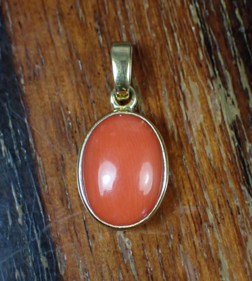 Appraisal: CORAL AND FOURTEEN KARAT YELLOW GOLD PENDANT bezel set with