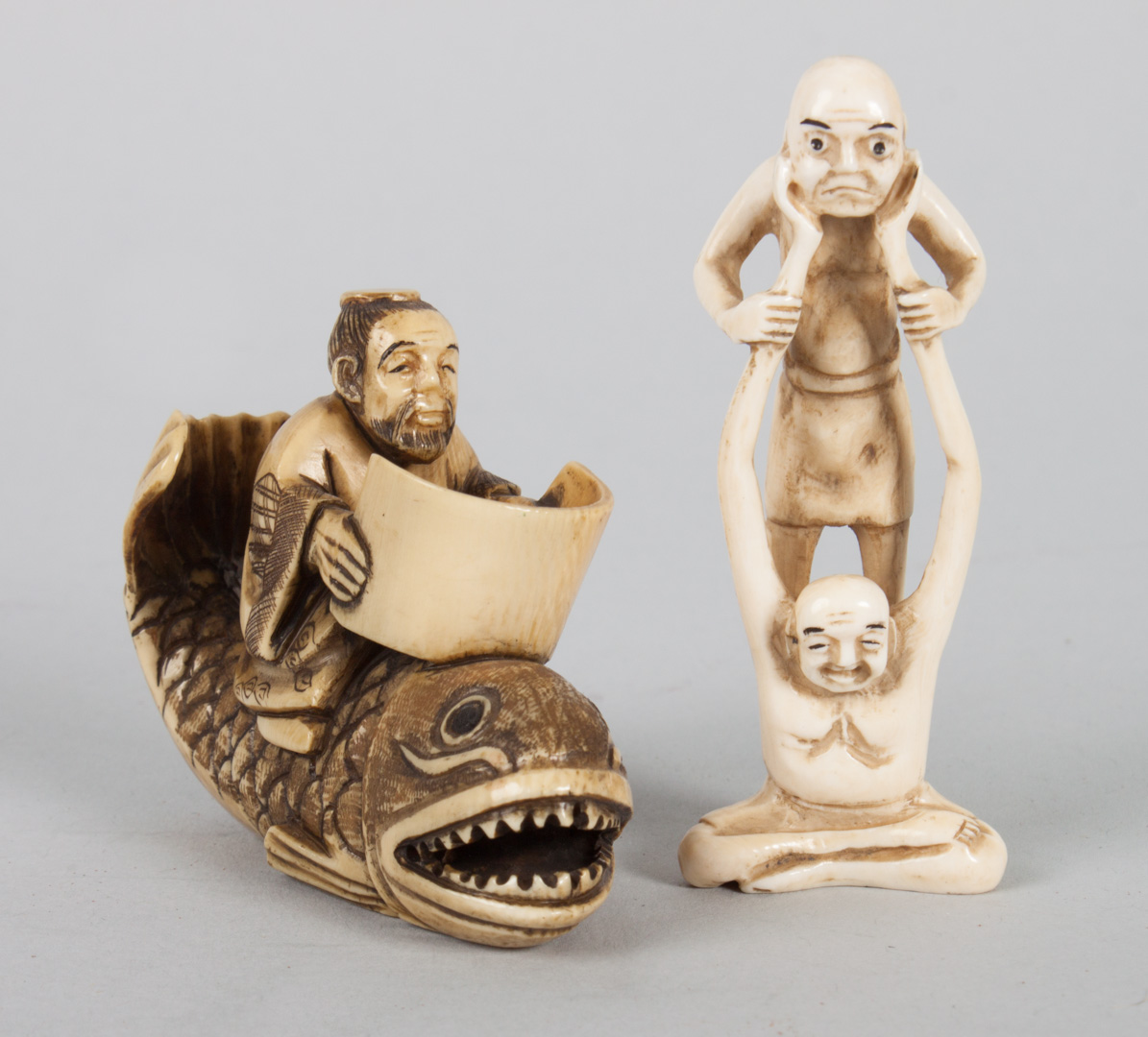 Appraisal: Two Japanese carved ivory netsukes scholar riding large vicious fish