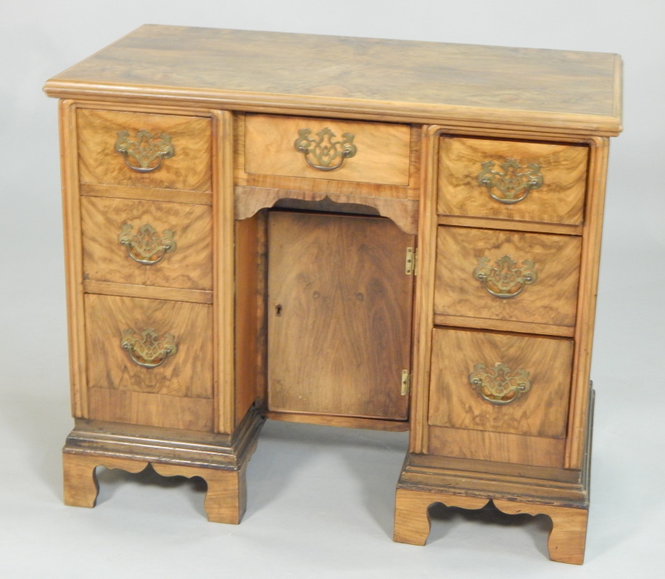 Appraisal: A walnut kneehole desk the highly figured top with a