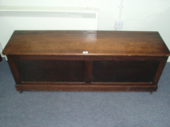 Appraisal: An oak blanket box the hinged lid above a panelled