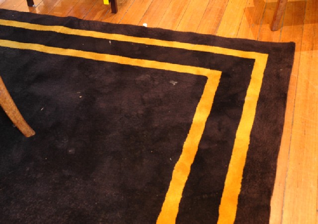 Appraisal: A MODERN WOOL CARPET Black ground with a gold border