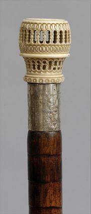 Appraisal: IVORY AND SILVER-MOUNTED CARVED WOOD WALKING STICK The handle a