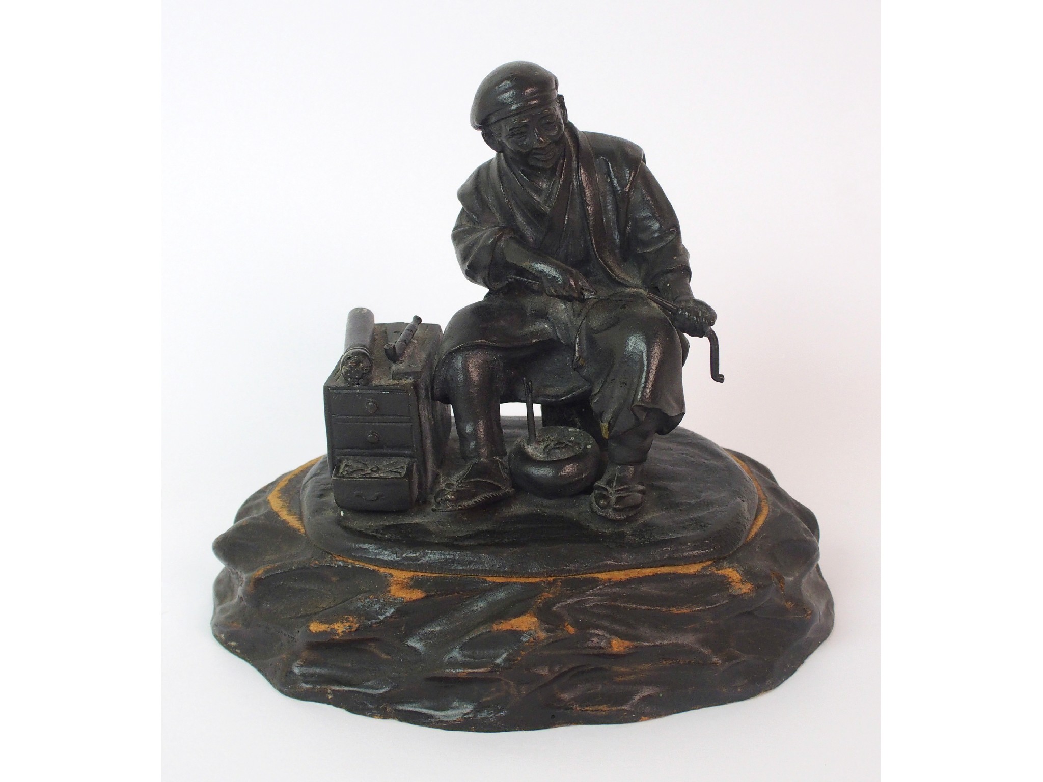 Appraisal: A Japanese bronze of an itinerant workerseated and hollowing out