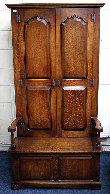 Appraisal: A TH CENTURY HARROD'S OAK SETTLE HALL CUPBOARD with twin