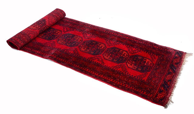 Appraisal: AN AFGHAN RED GROUND RUNNER with seven central medallions within