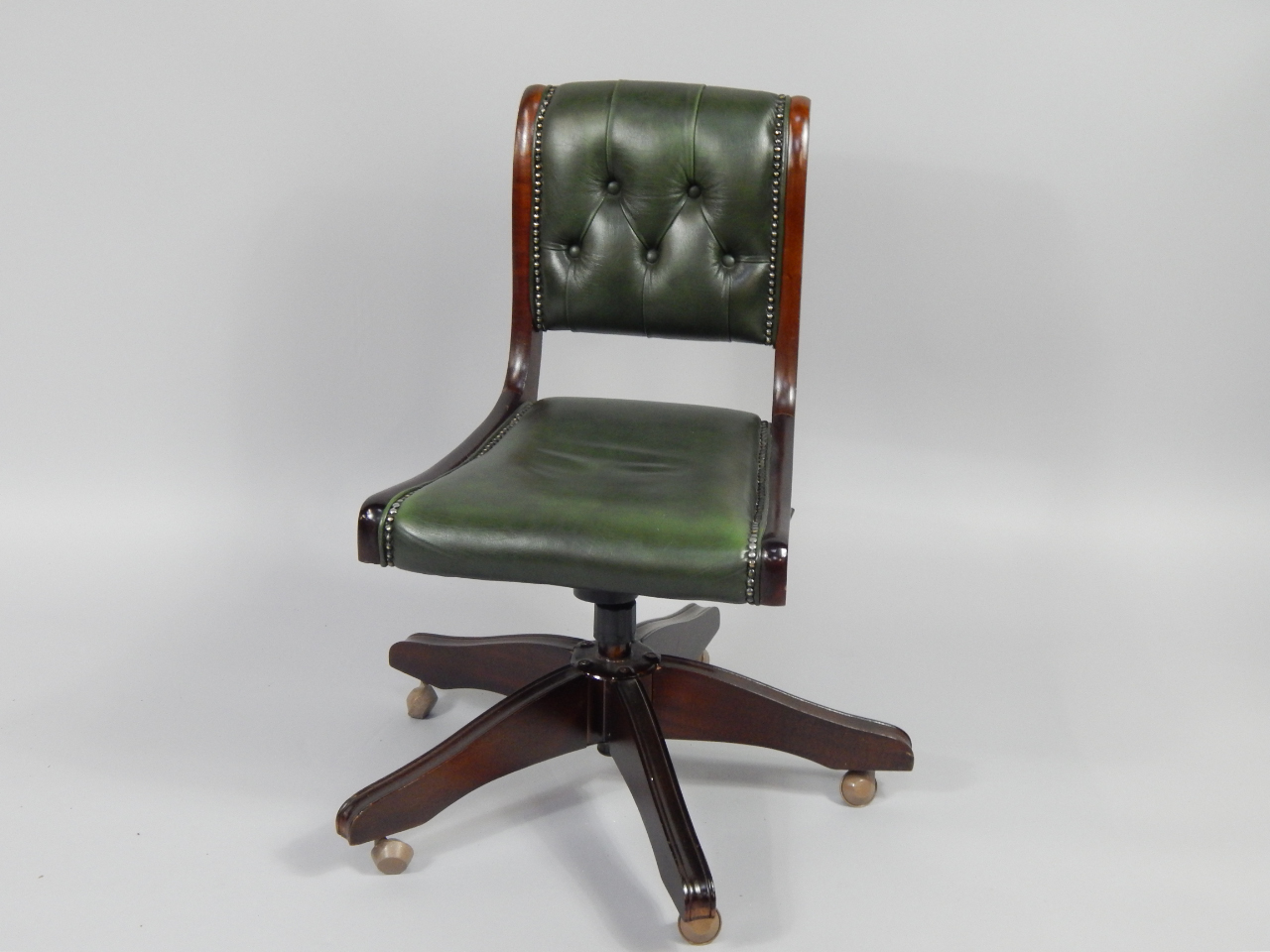 Appraisal: A mahogany and button upholstered green leather office swivel chair