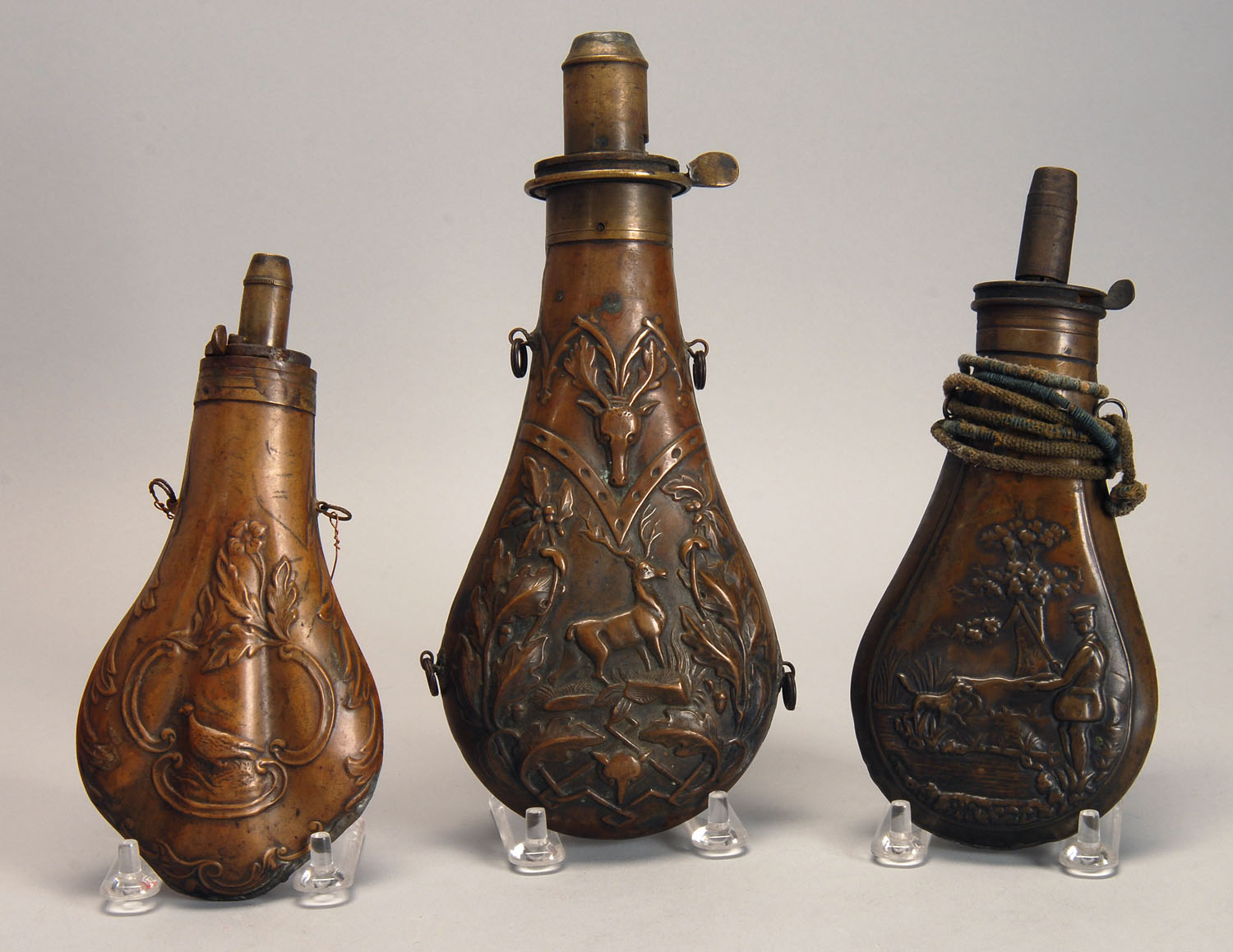 Appraisal: THREE COPPER POWDER FLASKS th CenturyOne decorated with a stag