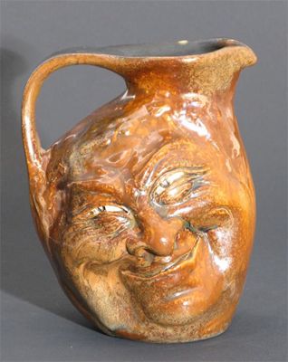 Appraisal: A Martin Brothers stoneware face jug modelled in low relief