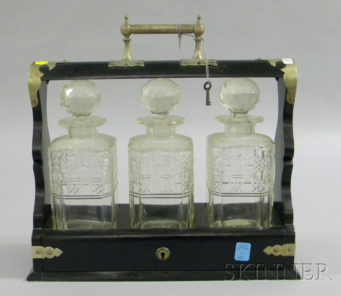 Appraisal: Victorian Ebonized Three-bottle Tantalus with three colorless cut glass bottles