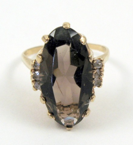 Appraisal: SMOKY QUARTZ AND FOURTEEN KARAT GOLD RING centering an oval-cut