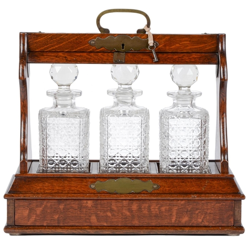 Appraisal: A Victorian brass mounted oak tantalus with three decanters of