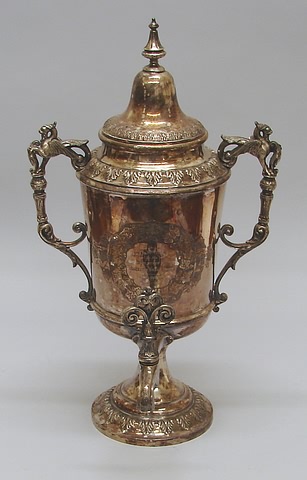 Appraisal: Bell-form cover with steeple finial twin griffon handles scrolled spigot