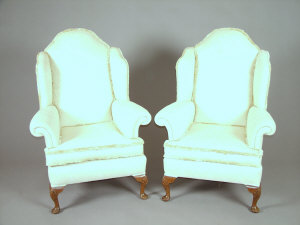 Appraisal: A pair of walnut and cream floral damask upholstered wingback