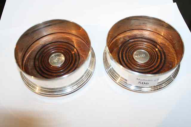 Appraisal: A PAIR OF SILVER BOTTLE COASTERS on turned wooden bases