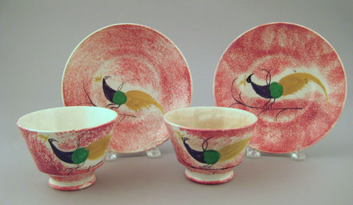 Appraisal: Two red spatter cups and saucers th c with peafowl