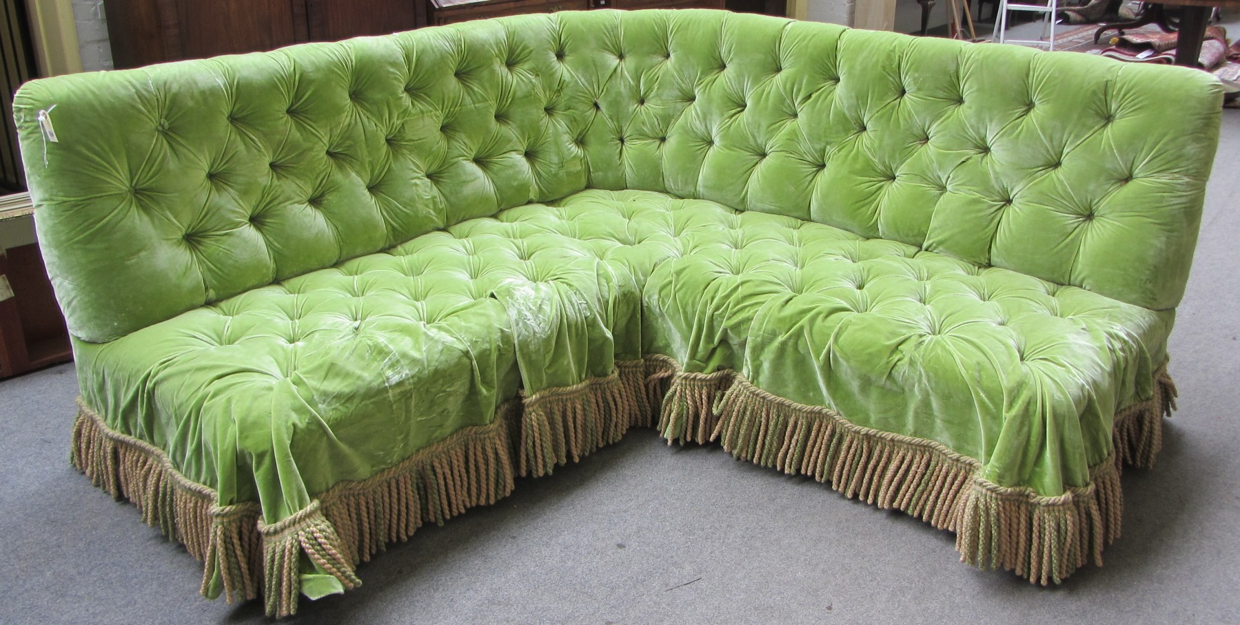 Appraisal: A large green velvet corner sofa with button upholstery and