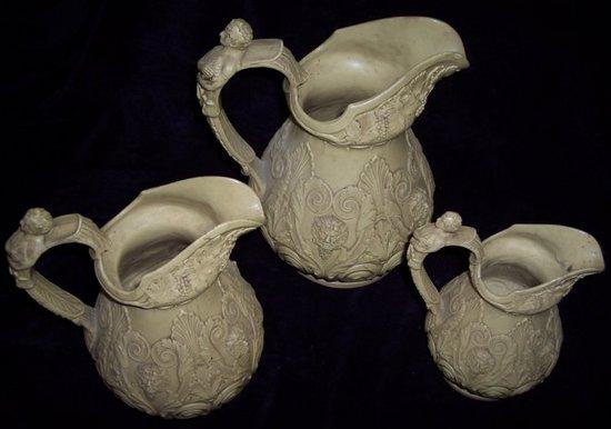 Appraisal: A graduated set of three pottery jugs decorated in relief