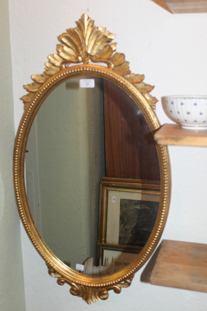 Appraisal: AN OVAL GILT WALL MIRROR with foliate mount high a