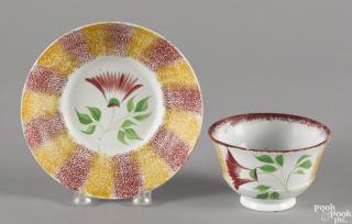 Appraisal: Red and yellow rainbow spatter cup and saucer with thistle