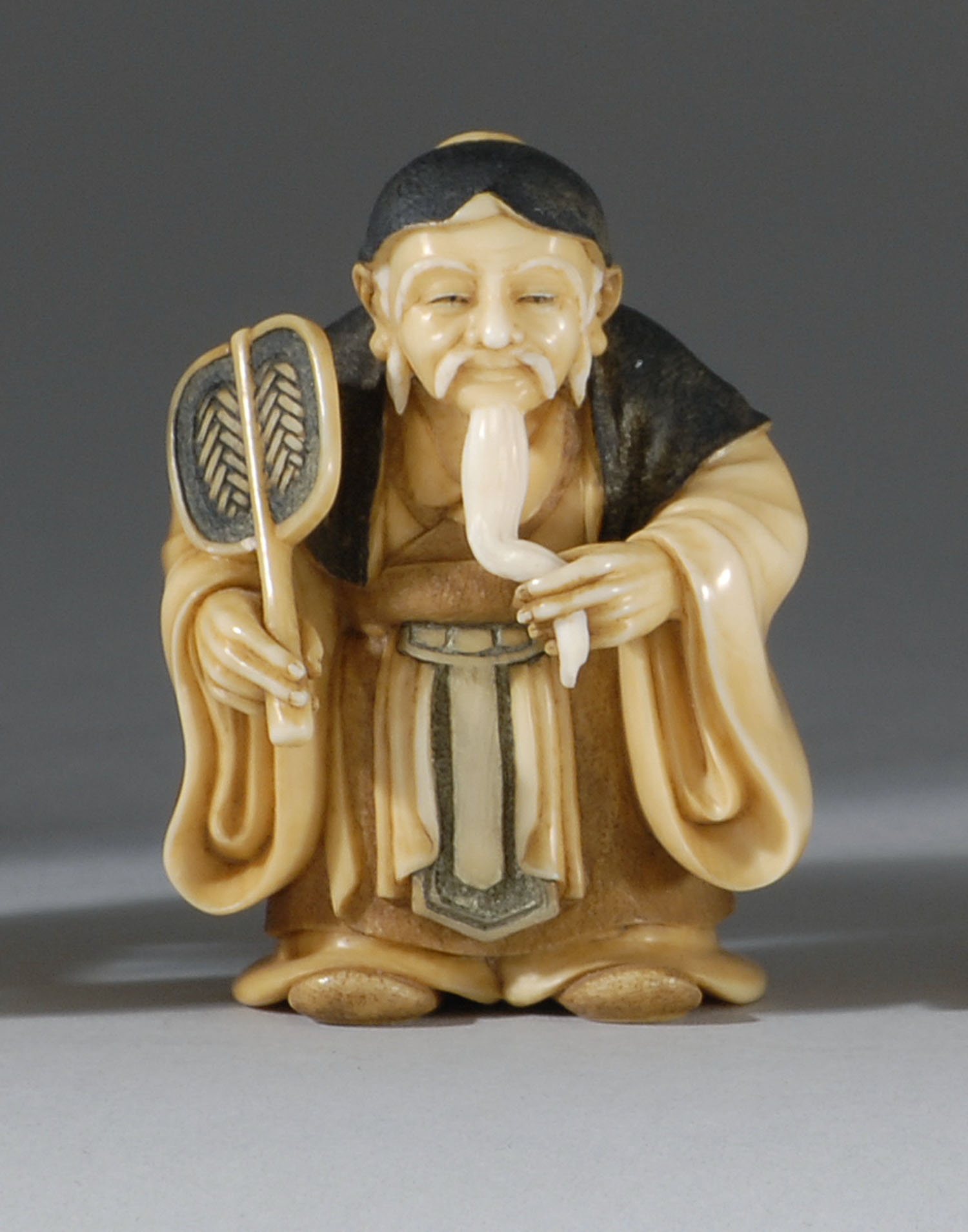 Appraisal: POLYCHROME IVORY NETSUKE ContemporaryBy Hozan Depicting an elderly man holding