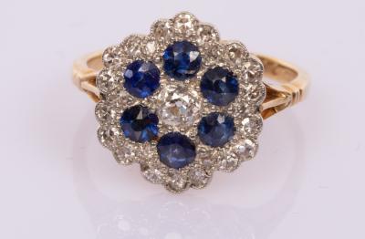 Appraisal: A diamond and sapphire flowerhead cluster ring the central diamond