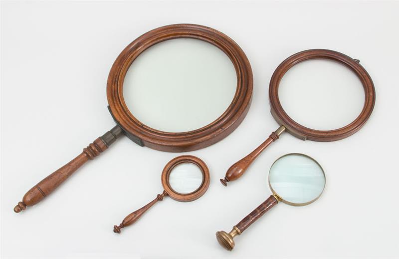 Appraisal: FOUR MAGNIFYING GLASSES The two largest brass-mounted walnut the smallest